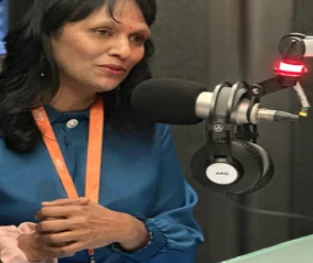 Meg Richy speaking in a radio studio interview